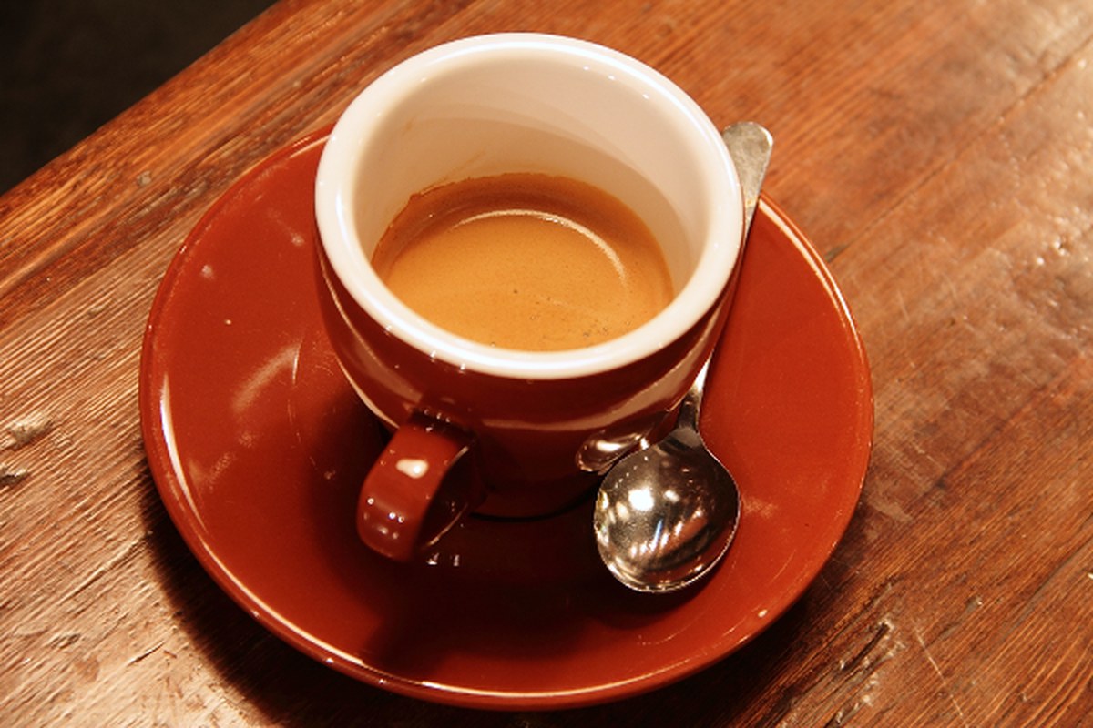 A small cup of espresso on a warm wooden table.