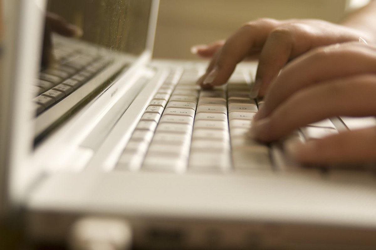 Hands typing on a laptop keyboard in warm natural light.